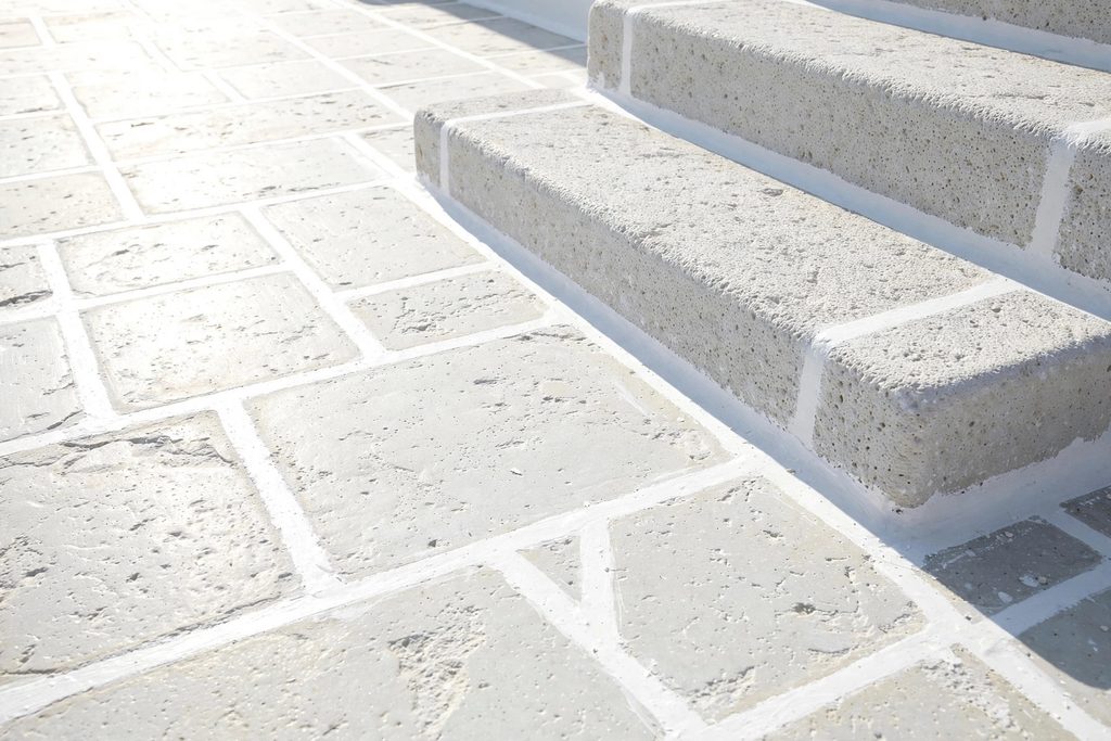 Close-up of traditional flat stone paving on a Greek island with all the joints meticulously outlined in bright white limewash.
