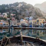 Neoclassical mansions in ochre and pastel colours rising in tiers above the calm harbor of Gialos on Symi at sunrise